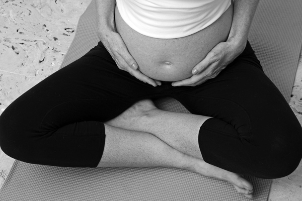 pregnant person holding their tummy with crossed legs