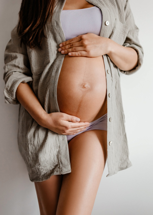 pregnant woman in khaki shirt holding belly