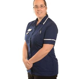 Portrait of Nickie the Midwife standing up in a navy blue uniform